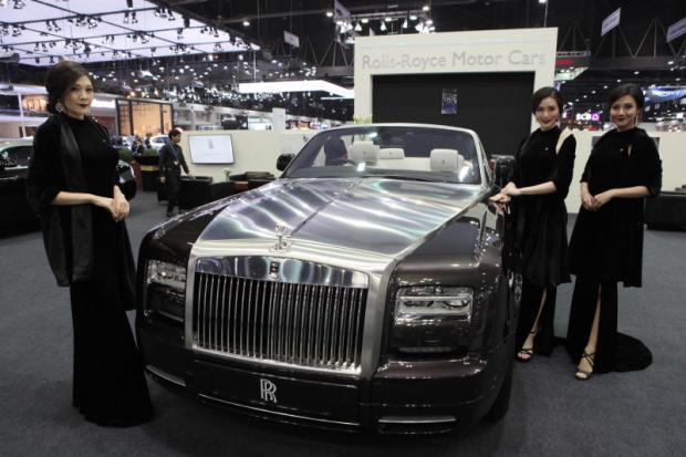 Presenters stand next to a Rolls-Royce car exhibited at the 33rd Thailand International Motor Expo 2016 at Challenger Hall, Impact Muang Thong Thani.
