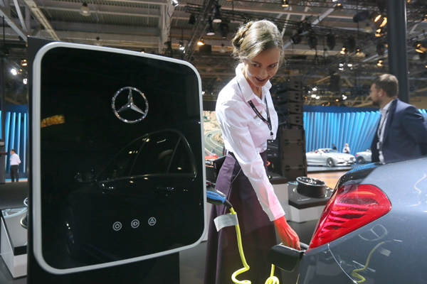 An employee charges a Mercedes-Benz hybrid car at an international automobile salon in Moscow. [Photo / Agencies]